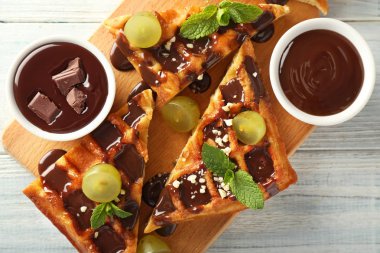 Üzüm ve ahşap tahta üzerinde çikolata sosu ile lezzetli waffle