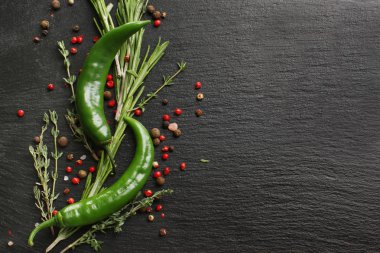 Yeşil biber, baharatlar ve siyah dokulu arka plan üzerinde taze otlar ile kompozisyon