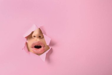 Dudakların güzel genç kadının kalçası pembe kağıt delikten görünür