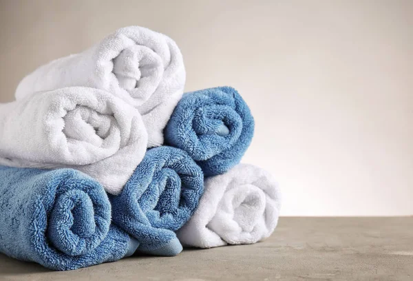 Rolled clean towels on table against light background