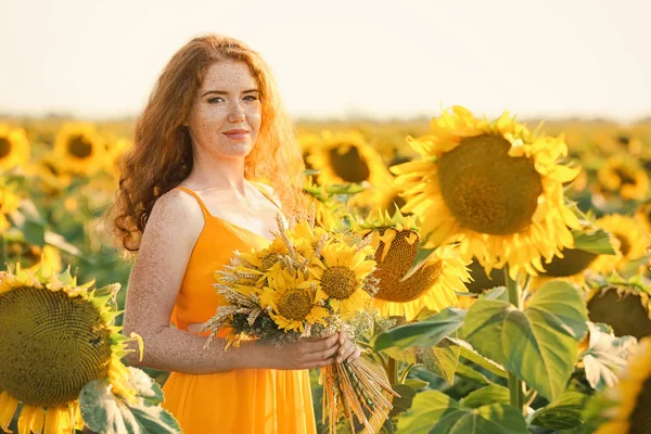 Beautiful redhead woman in sunflower field on sunny day