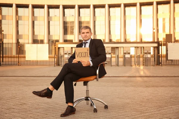 Empresário Segurando Pedaço Papelão Com Palavra Vacant Enquanto Sentado Escritório — Fotografia de Stock