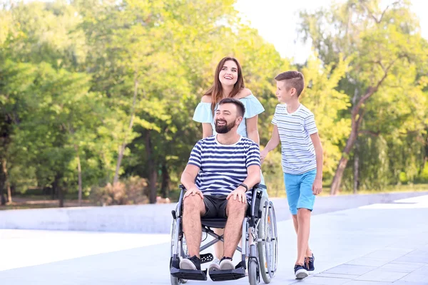 Young man in wheelchair with his family walking outdoors