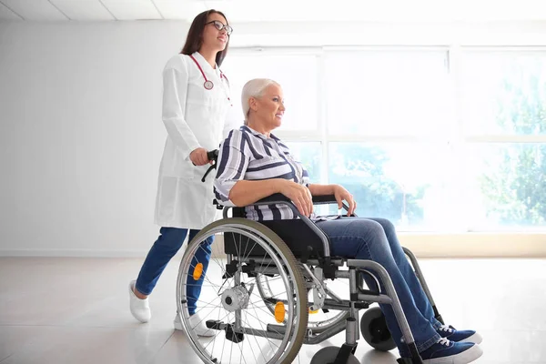 Handicapped mature woman with young female doctor in clinic