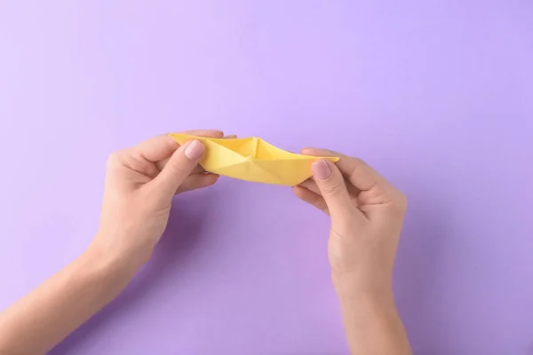 Woman with origami boat on color background