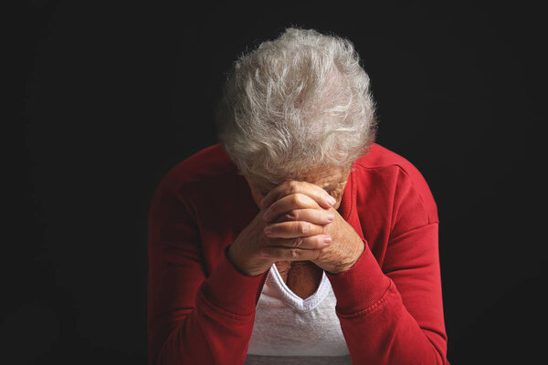 Депрессивная пожилая женщина на темном фоне
