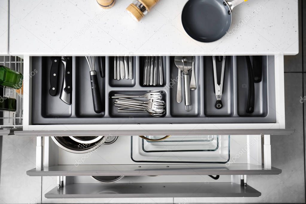 Set of clean kitchenware and utensils in drawers