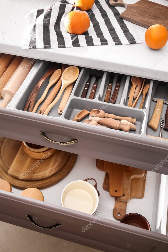 Set of clean kitchenware and utensils in open drawers