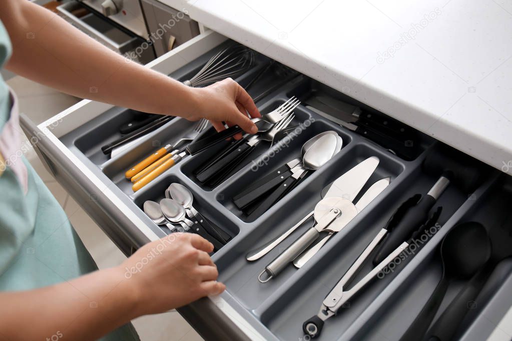 Woman putting fork into kitchen drawer