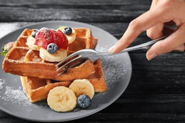 Lezzetli waffle ve çilek ahşap arka plan üzerinde yemek kadın