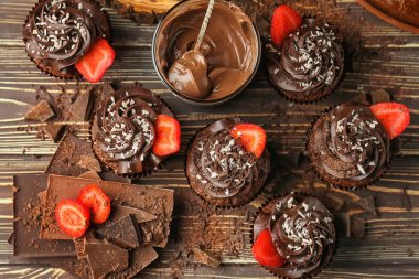 Çilek ve çikolata ahşap masa üzerinde parçaları ile lezzetli cupcakes