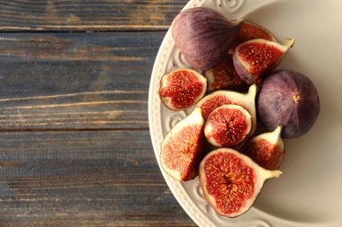 Ahşap masa üzerinde taze olgun incir ile plaka