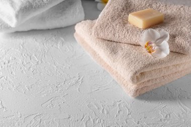 Beyaz masa üzerinde çiçek ve sabun çubuklu temiz yumuşak havlu yığını