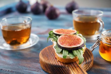 Olgun incir, otlar ve ahşap tahta üzerinde krem peynir ile lezzetli sandviç