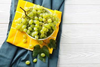Beyaz ahşap masa üzerinde olgun tatlı üzüm ile kase