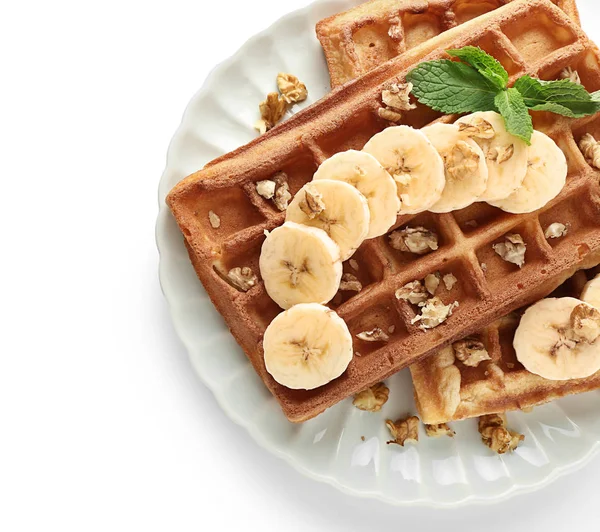 Delicious waffles with banana slices and nuts on white background