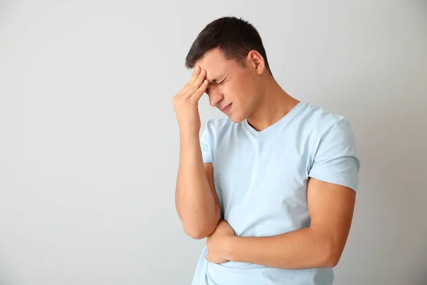 Young Man Suffering Headache Light Background — Stock Photo, Image