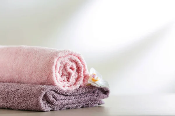 Clean soft towels with flower on light table