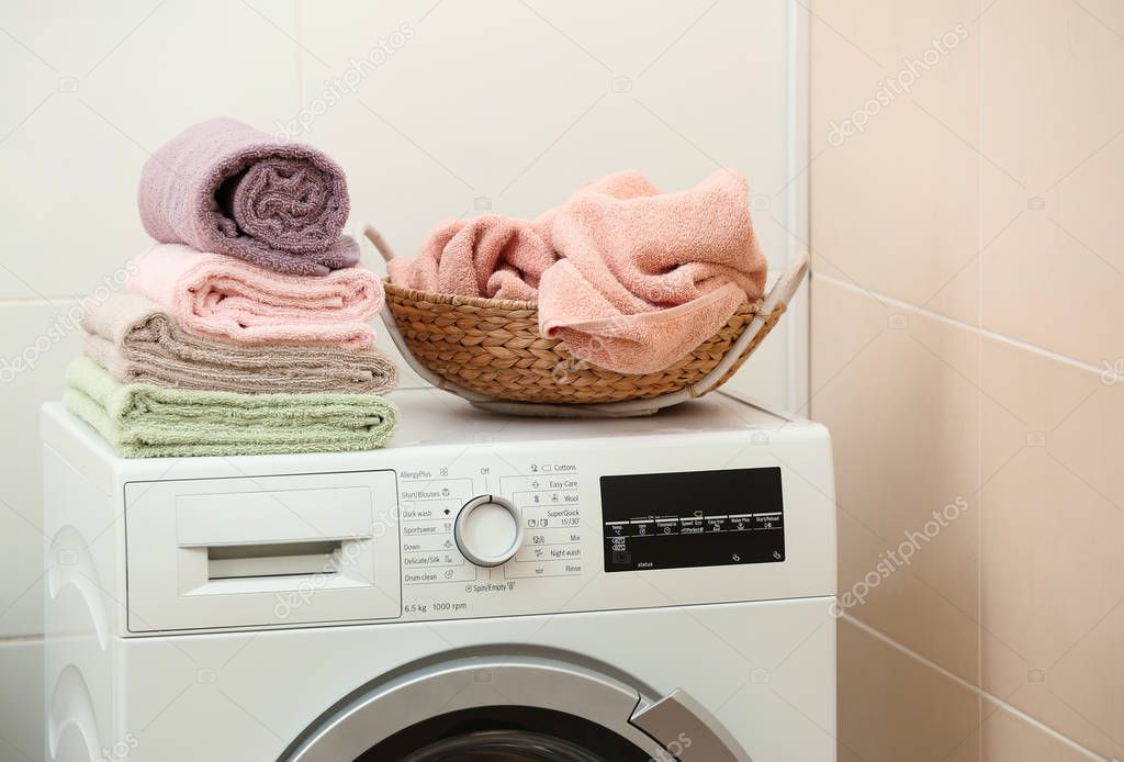Stack of clean towels on washing machine in bathroom