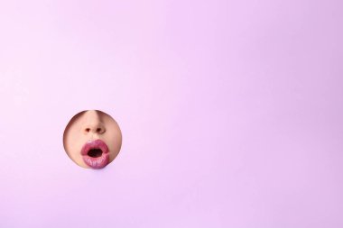 Dudaklar genç kadının renk kağıt delikten görünür