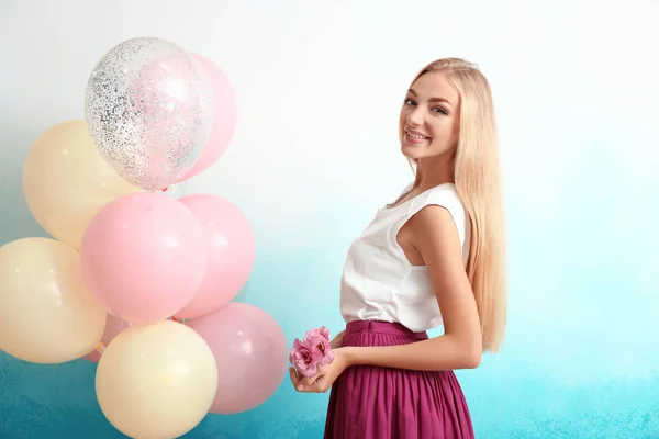 Schöne Junge Frau Mit Luftballons Und Blumen Auf Farbigem Hintergrund — Stockfoto