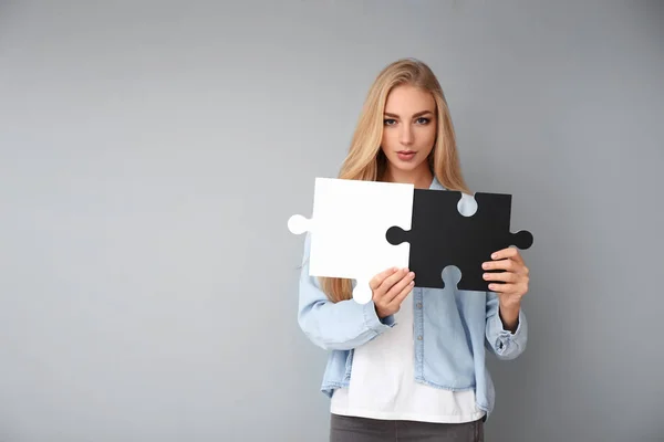 Ung Kvinna Matchande Bitar Pussel Grå Bakgrund — Stockfoto