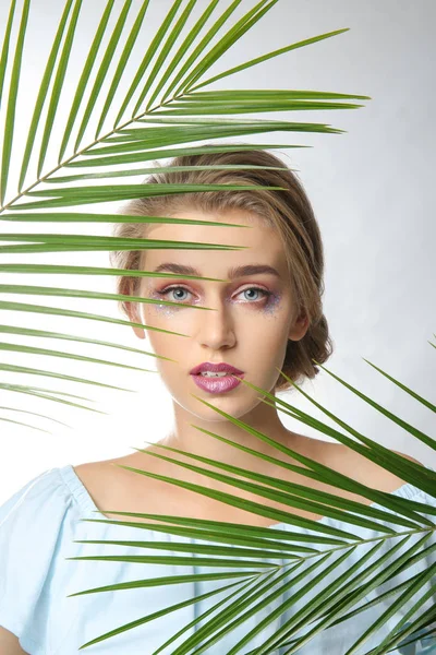 Ung Kvinna Med Vackra Makeup Och Tropiska Blad Vit Bakgrund — Stockfoto