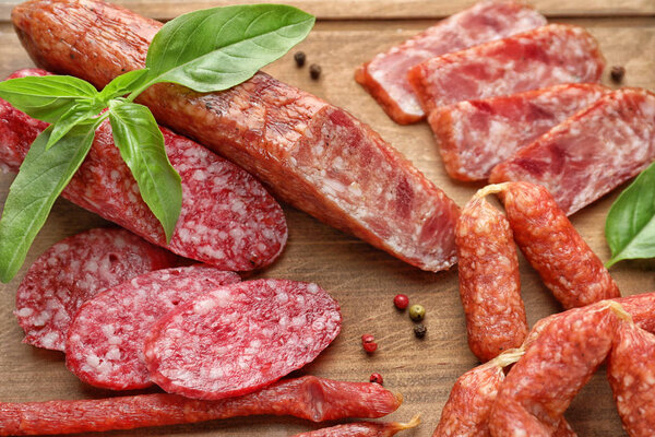 Различные виды копченых колбас на деревянной доске, крупным планом
