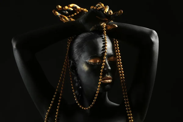 美丽的妇女与黑色和金色的油漆在她的身体持有珠反对黑暗背景 — 图库照片
