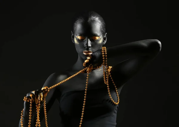 Красивая Женщина Черно Золотой Краской Теле Держа Бусы Темном Фоне Лицензионные Стоковые Изображения