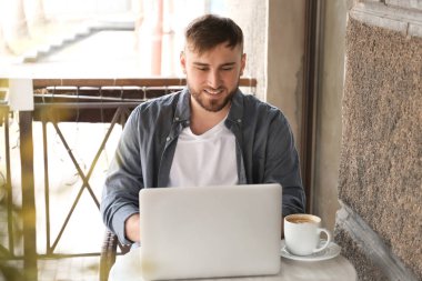 Kafede çalışan dizüstü bilgisayar ile genç serbest meslek