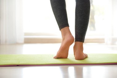 Evde yoga yapan genç bir kadın.