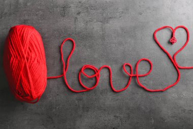 Gri arka plan üzerinde kırmızı iplik kelime aşk yapılmış