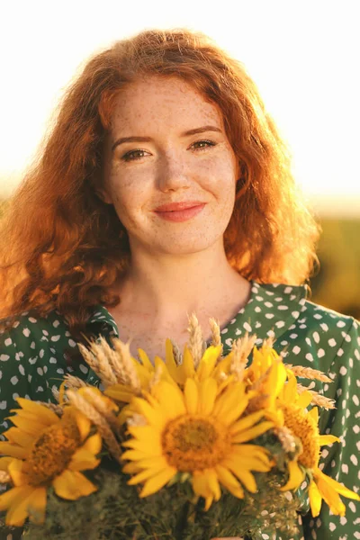 Beautiful redhead woman in sunflower field on sunny day
