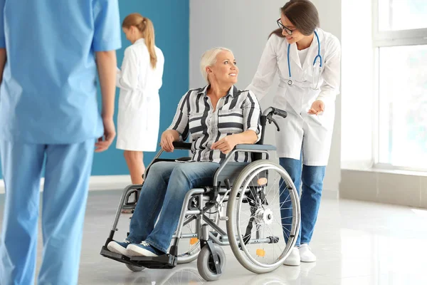 Handicapped mature woman with young female doctor in clinic