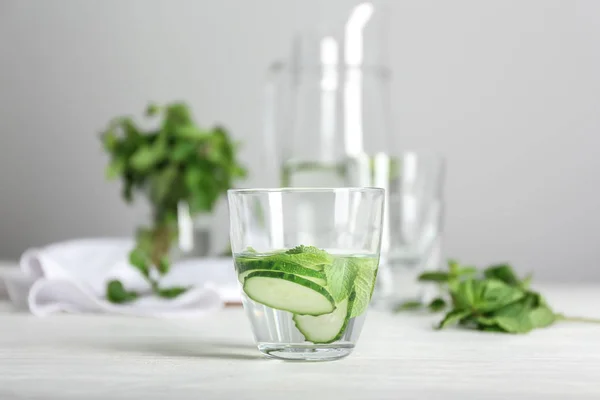 Glass of tasty fresh cucumber water on white table