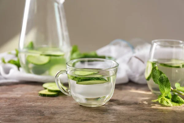 Glass cup of tasty fresh cucumber water on wooden table