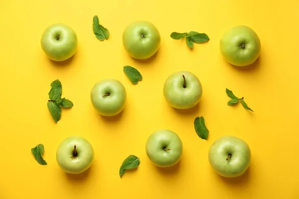 Ripe fresh apples with mint on color background