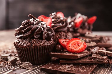 Çilek ve çikolata ahşap masa üzerinde parçaları ile lezzetli cupcakes
