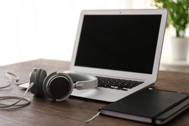 Laptop ve defter ahşap masa üzerinde kulaklık