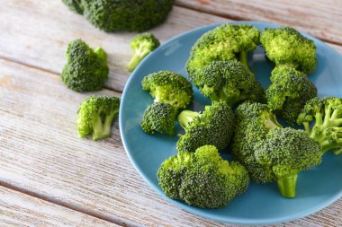 Ahşap masa üzerinde taze brokoli ile plaka