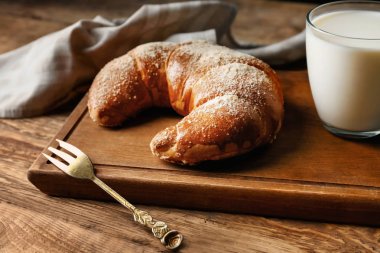 Lezzetli taze hilal rulo bardak süt ile ahşap tahta üzerinde