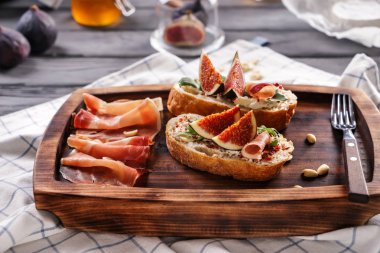 Olgun incir ve ahşap tahta üzerinde prosciutto ile lezzetli sandviçler