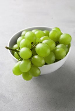 Gri arka plan üzerinde olgun tatlı üzüm ile kase