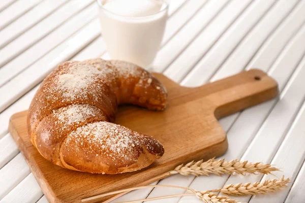 Lezzetli taze hilal ekmek ve bir bardak süt beyaz masada ahşap tahta