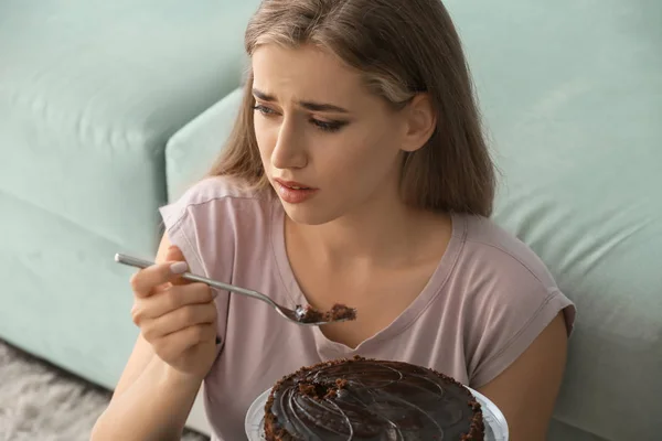 Lonely depressed woman eating chocolate cake at home