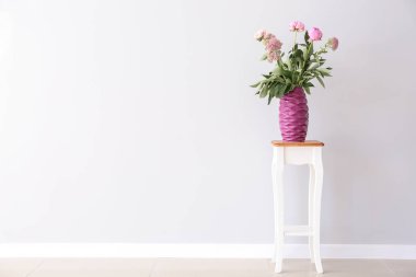 Dışkı ışık duvarının yakınında üzerinde güzel pembe çiçekli vazo