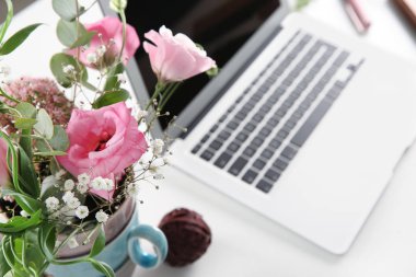 Vazo ile güzel çiçekler ve beyaz masa üstünde laptop