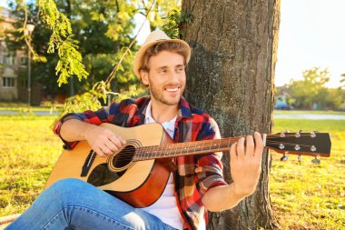 Yakışıklı delikanlı Park'ta dinlenme gitar ile