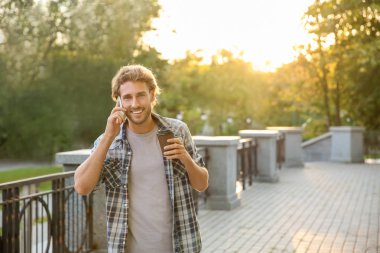 Cep telefonu Park konuşurken kahve ile yakışıklı genç